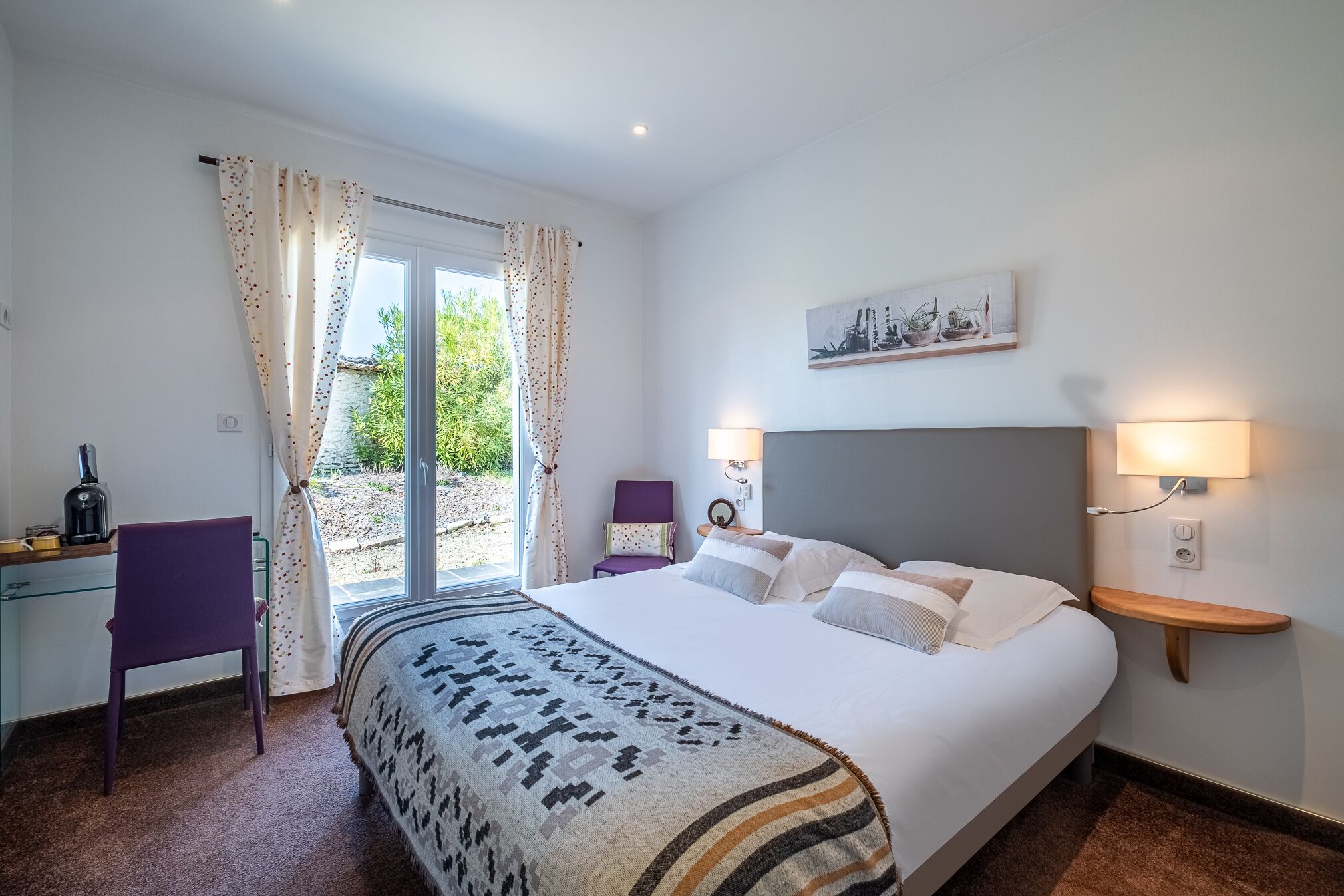 Ein Schlafzimmer mit einem Bett, einem Schreibtisch, einem Stuhl, einem Fenster mit Vorhängen und einer Wandlampe.