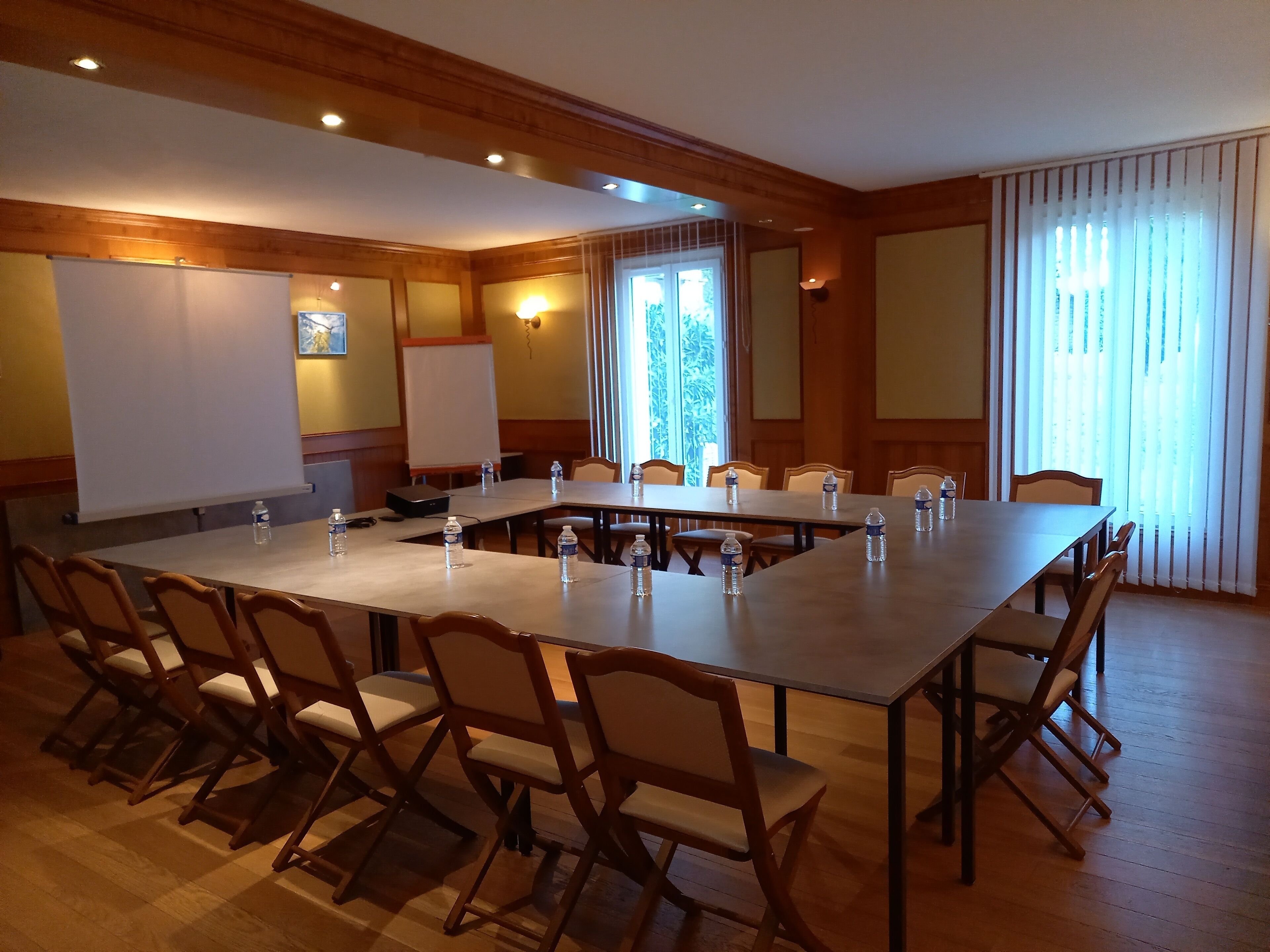 A conference room with a long table, chairs, a whiteboard, and a projector.