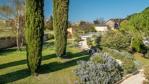 Ein gepflegter Garten mit hohen, schmalen Bäumen und verschiedenen Sträuchern.