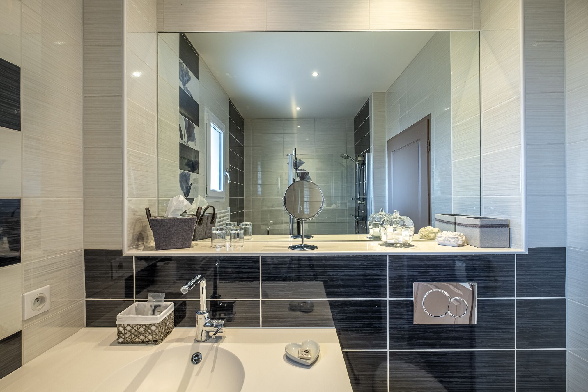 A modern bathroom with a large mirror, a sink, and a shower area.