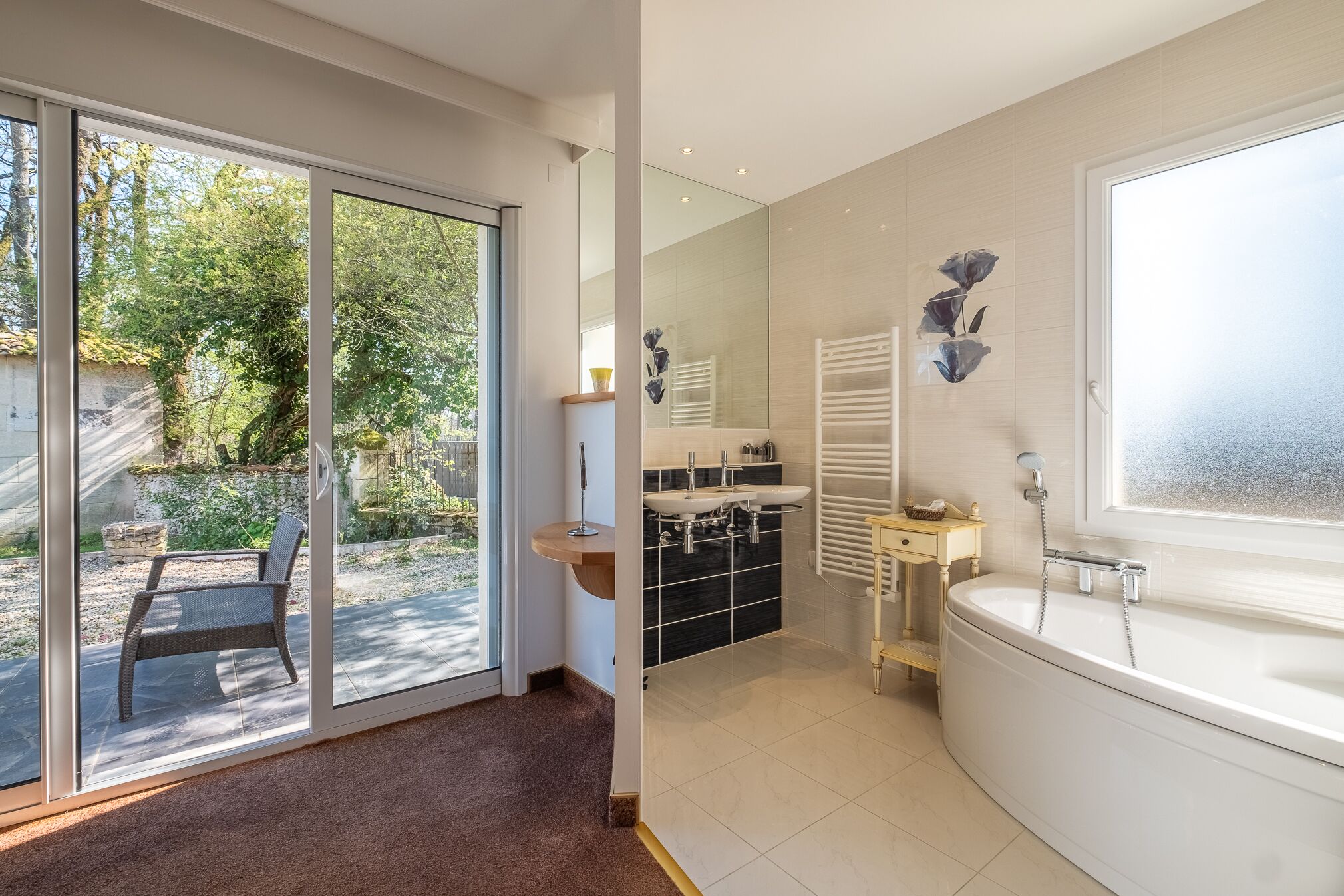 A modern bathroom with a large bathtub, a glass-enclosed shower area, and a view of the outdoors.