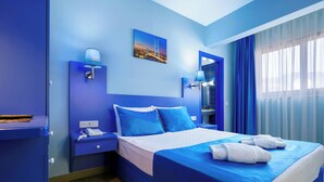 Habitación de hotel con cama, mesita de noche, lámpara, teléfono y un cuadro en la pared.