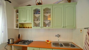 A kitchen with green cabinets, a gas stove, a sink, and a fruit bowl. - Alan studio Apartment in Rovinj downtown (Rovinj)