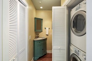 A compact laundry room with a washing machine, a sink, and a cabinet.
