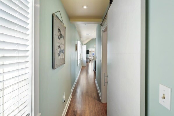A narrow hallway with wooden flooring and light green walls.