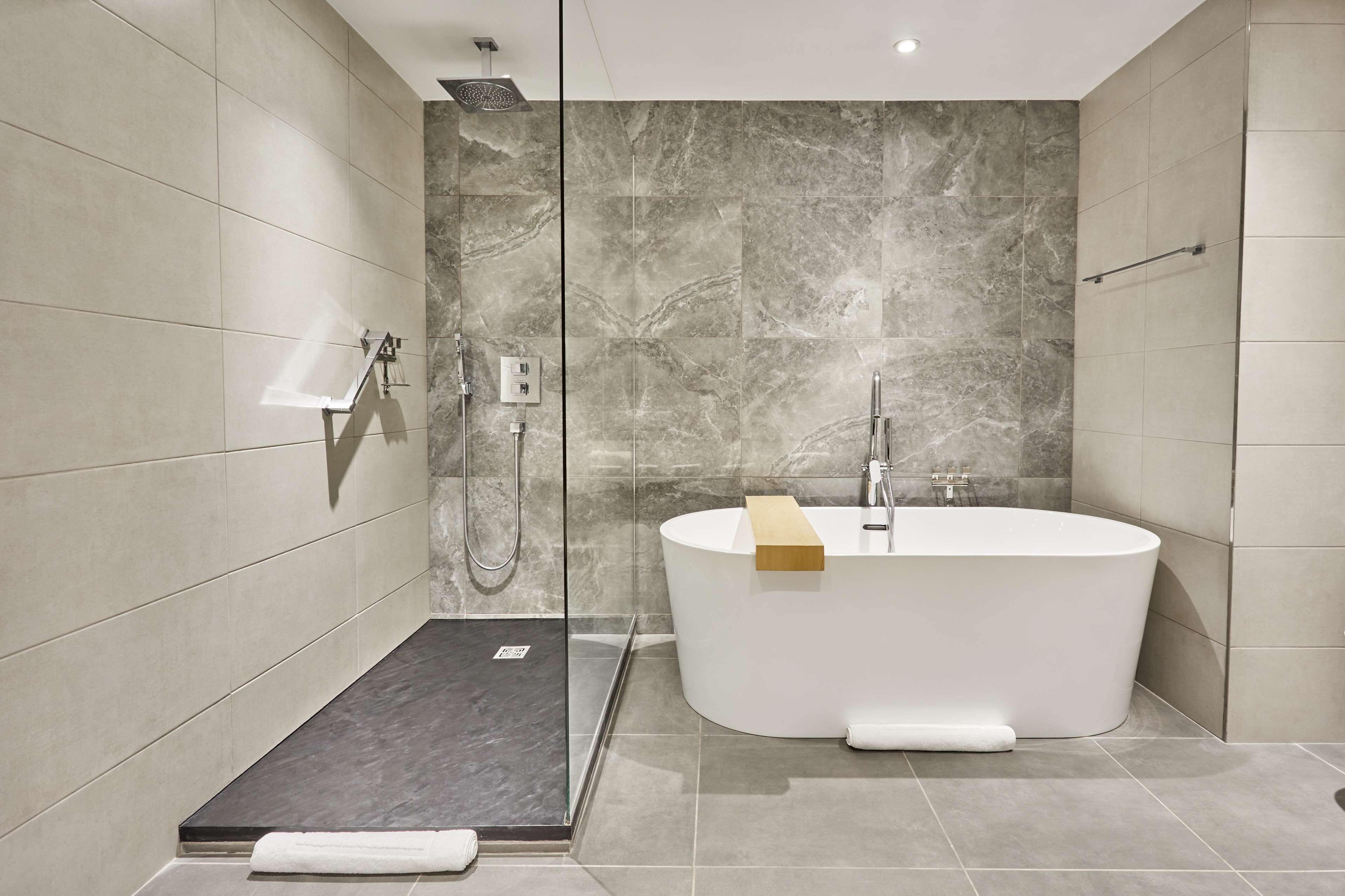 A modern bathroom with a freestanding bathtub, a glass shower enclosure, and a small step for accessibility.