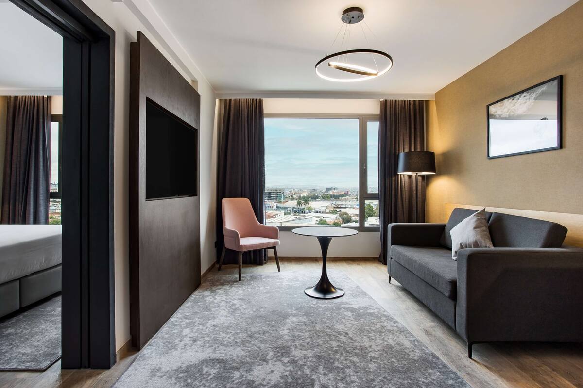 Una habitación de hotel moderna con sofá, sillón y una pequeña mesa.