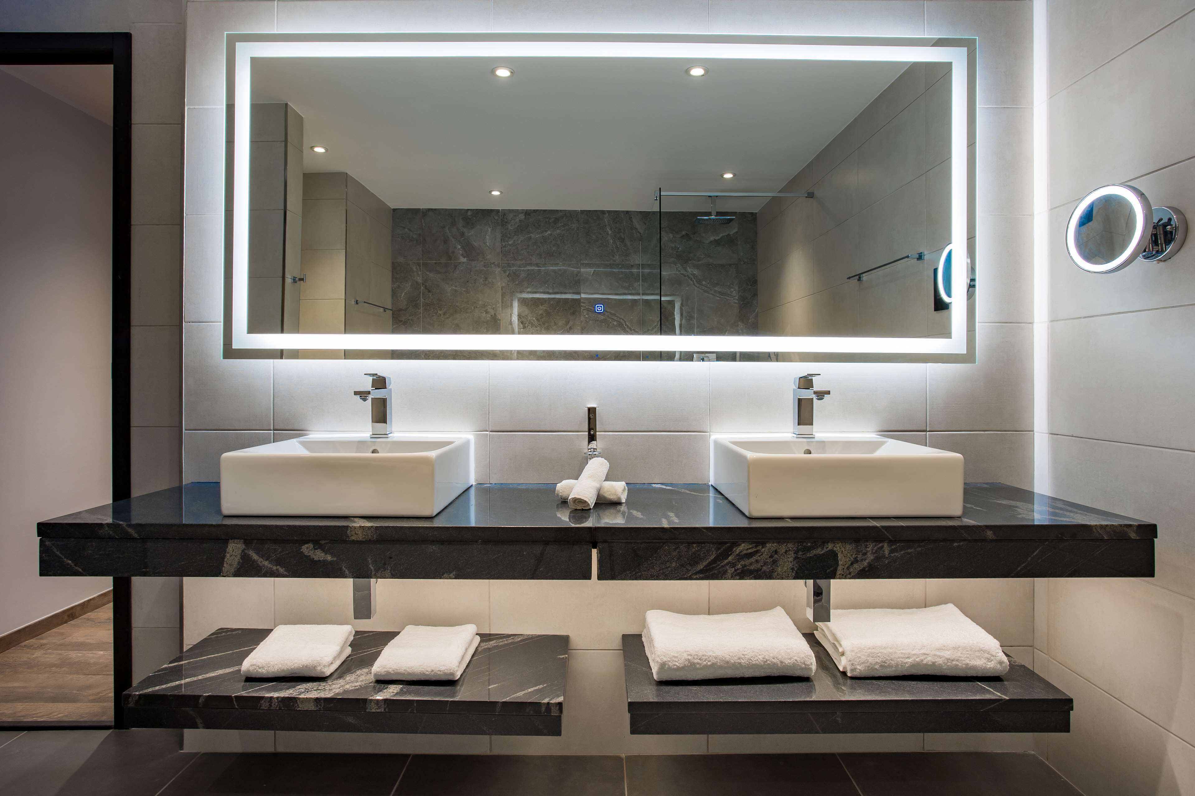 Un bagno moderno con due lavandini, un grande specchio e asciugamani integrati.