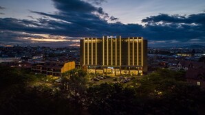 Un hotel moderno con una fachada vertical destacada, varios pisos y una entrada bien iluminada.