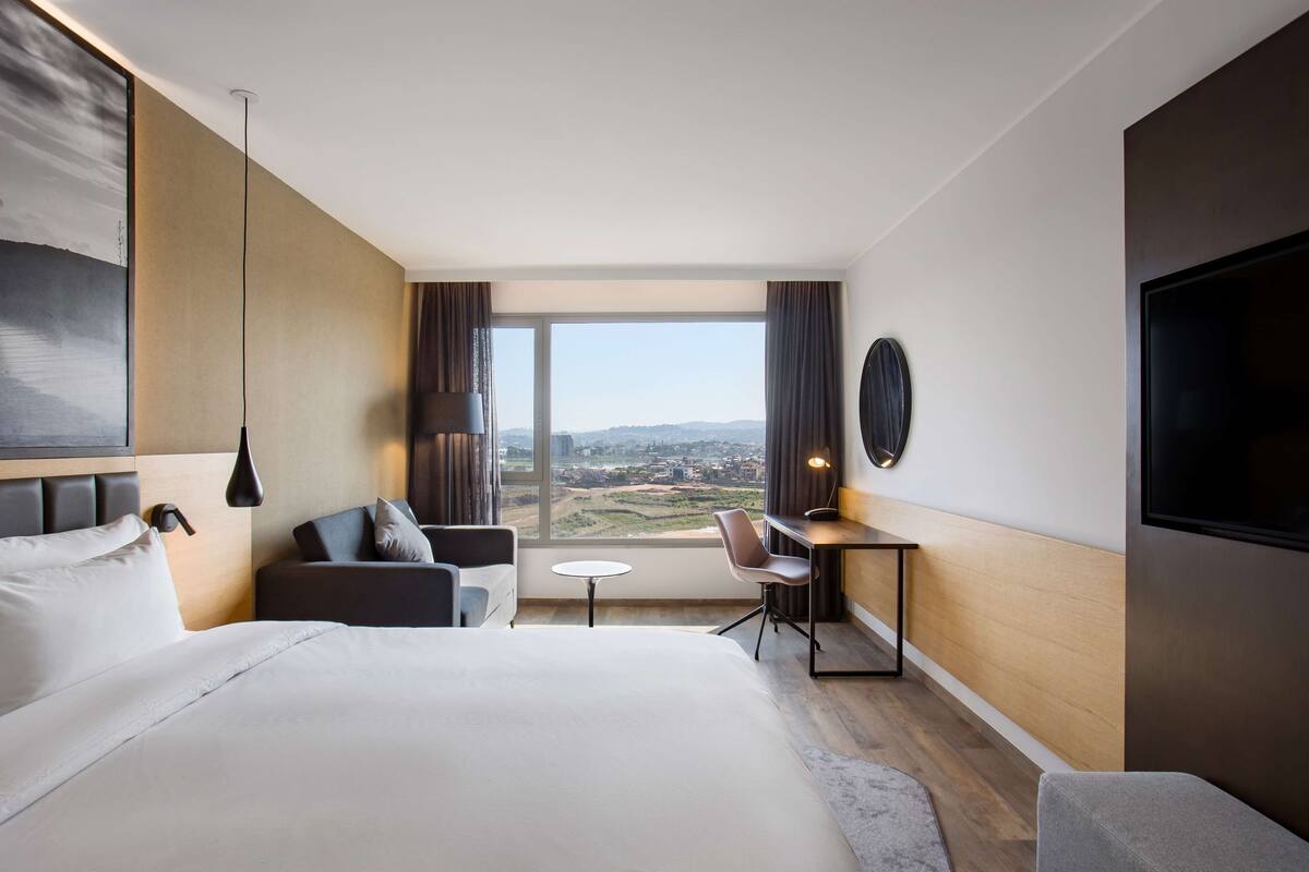Una habitación de hotel moderna con una cama grande, un escritorio, una silla y un televisor.