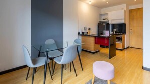 Una cocina moderna con horno empotrado y comedor con mesa de vidrio y cuatro sillas.