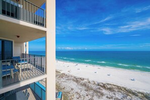 Un balcon aménagé avec du mobilier d’extérieur, offrant une vue sur la plage et l’océan.