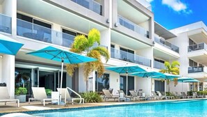 Ein modernes Hotel mit Schwimmbad, Liegestühlen und Sonnenschirmen.