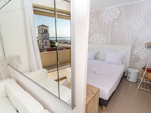 Un dormitorio moderno con una cama grande, un balcón con vista a una torre de reloj y un adorno de pared.