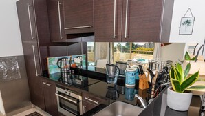 Una cucina moderna con mobili scuri, elettrodomestici in acciaio inossidabile e un piano di lavoro nero.