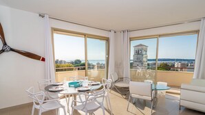 Un appartamento moderno con un balcone, ampie finestre e un'area pranzo per quattro persone.