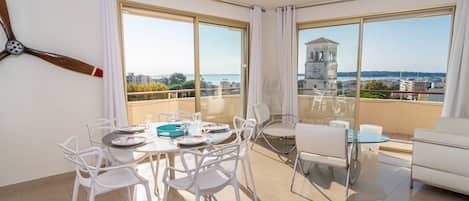 A modern apartment with a balcony, large windows, and a dining area set up for four people.