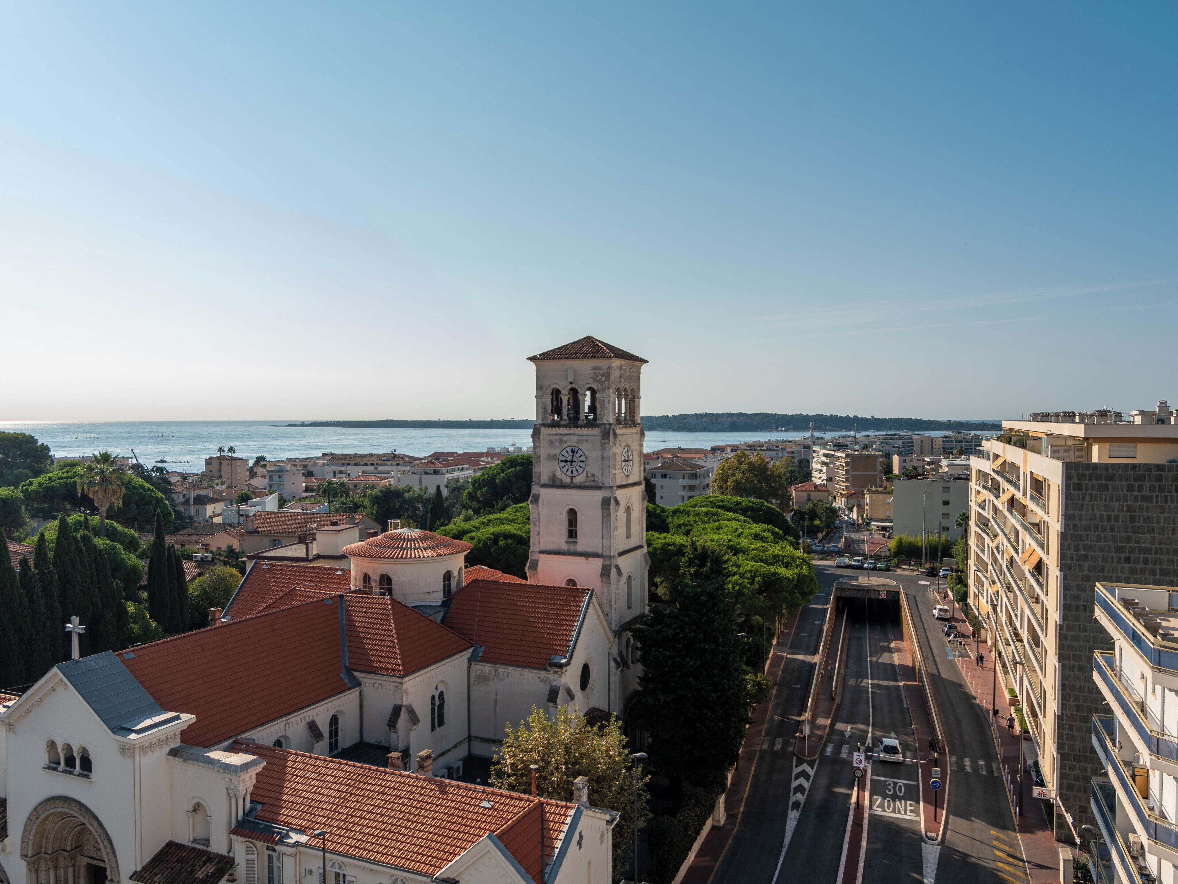 Une église historique dotée d’un clocher, entourée d’immeubles et offrant une vue dégagée sur la mer.