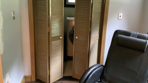 A room with a closed sliding door, a washing machine, and a black leather chair. - SKI, FISH, GOLF, RAFT, HIKE, HUNT, ATV ride, RELAX, 4 bdr home on wooded ADK lot (Malone)