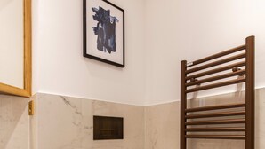 A modern bathroom with a toilet, a sink, a marble-tiled wall, a framed artwork, and a towel rack. - St Georges - Superb studio in the heart of Paris (Paris)