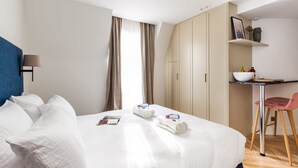 A hotel room with a bed, a desk, a chair, and a wardrobe. - St Georges - Superb studio in the heart of Paris (Paris)