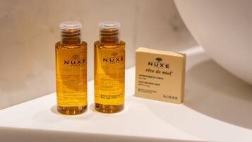 Two bottles of Nuxe shampoo and a box on a white surface.