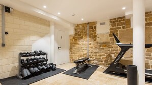 A gym with exercise equipment, a stone wall, and a door. - St Georges - Superb studio in the heart of Paris (Paris)