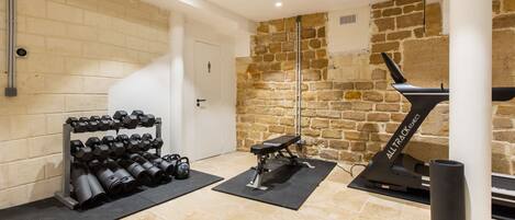 A gym with exercise equipment, a stone wall, and a door.