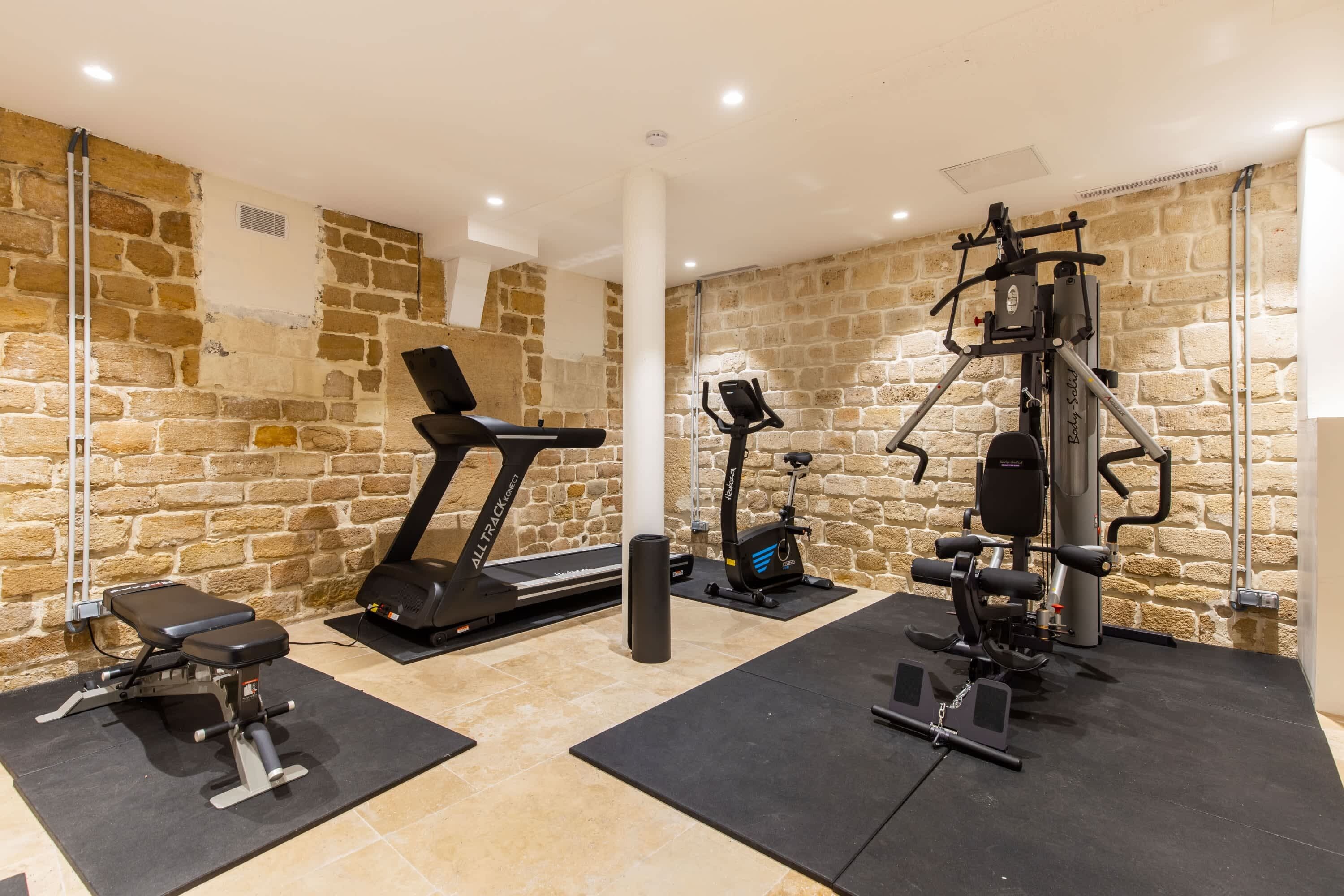 A gym with a treadmill, weight bench, and various exercise machines.
