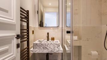 A modern bathroom with a marble sink, a glass shower enclosure, and a toilet.