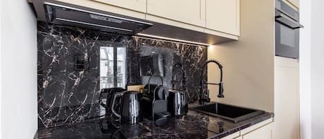 A modern kitchen with a black marble countertop, a built-in stove, and a stainless steel sink.