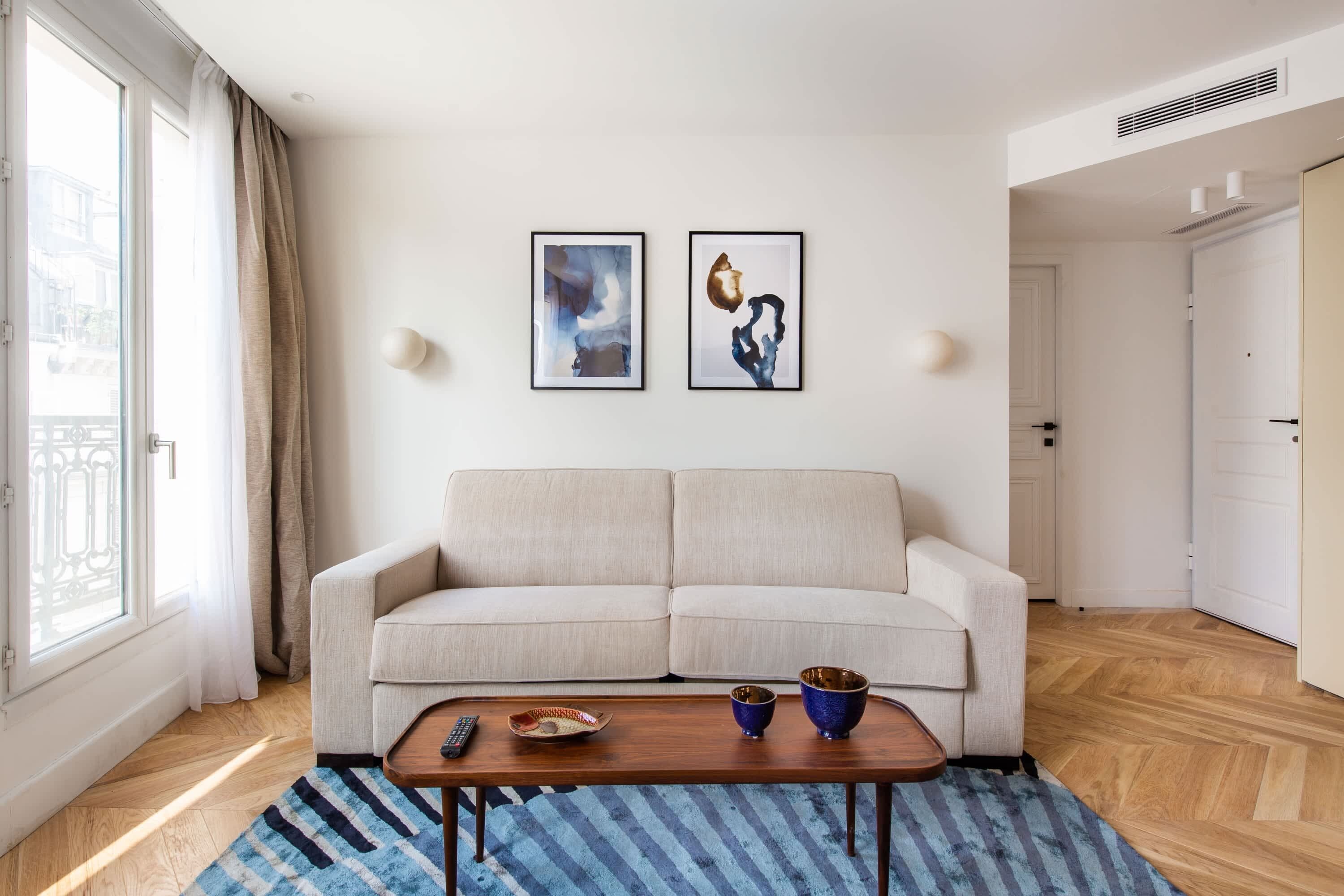 A modern living room with a sofa, a coffee table, and two framed artworks on the wall.
