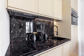 A modern kitchen with a black marble countertop, a built-in stove, and a stainless steel sink.