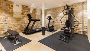 Ein Fitnessstudio mit Laufband, Gewichtbank und verschiedenen Trainingsgeräten.