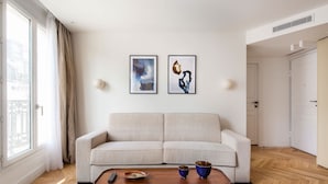 Ein modernes Wohnzimmer mit einer Couch, einem Couchtisch und zwei gerahmten Kunstwerken an der Wand.