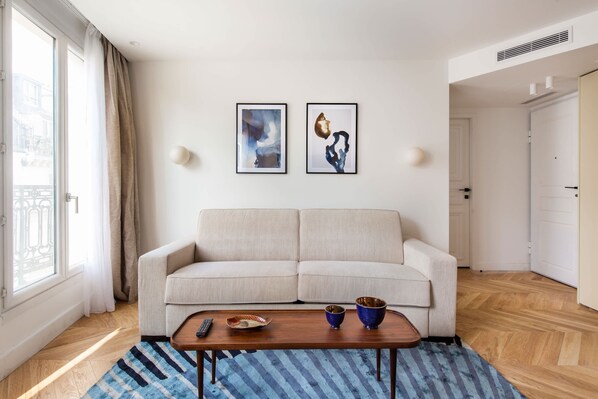 A modern living room with a sofa, a coffee table, and two framed artworks on the wall.
