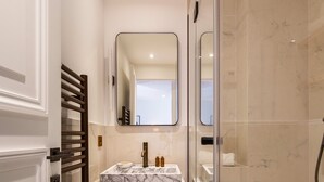 A modern bathroom with a marble sink, a glass shower enclosure, and a walk-in shower. - St Georges - One Bedroom in Paris South Pigalle (Paris)