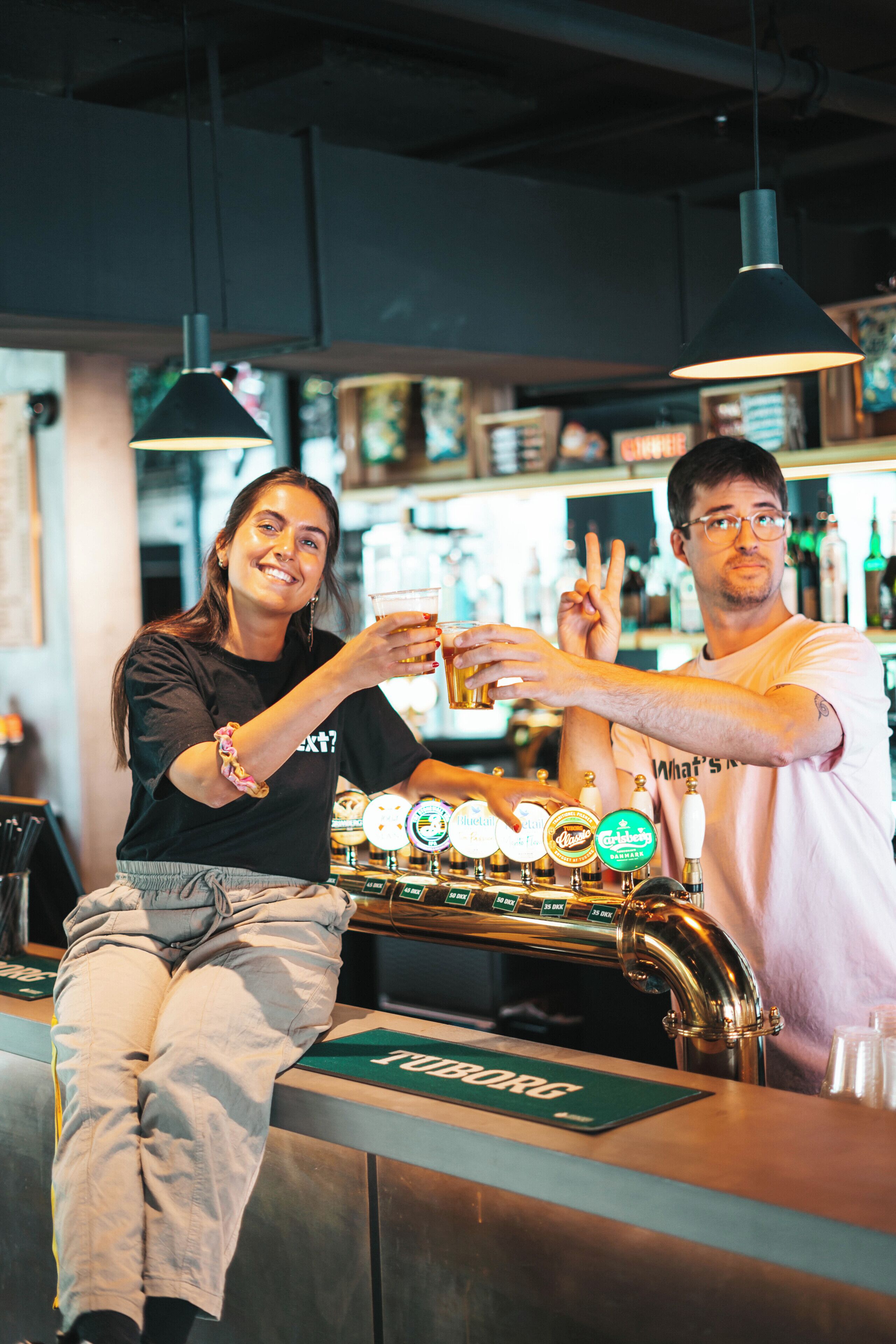 Un coin bar avec une tireuse à bière et deux personnes tenant des verres.