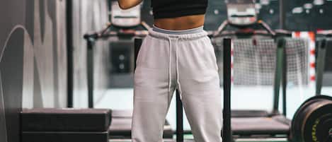 A person exercising on a mat in a gym with weightlifting equipment and treadmills in the background.