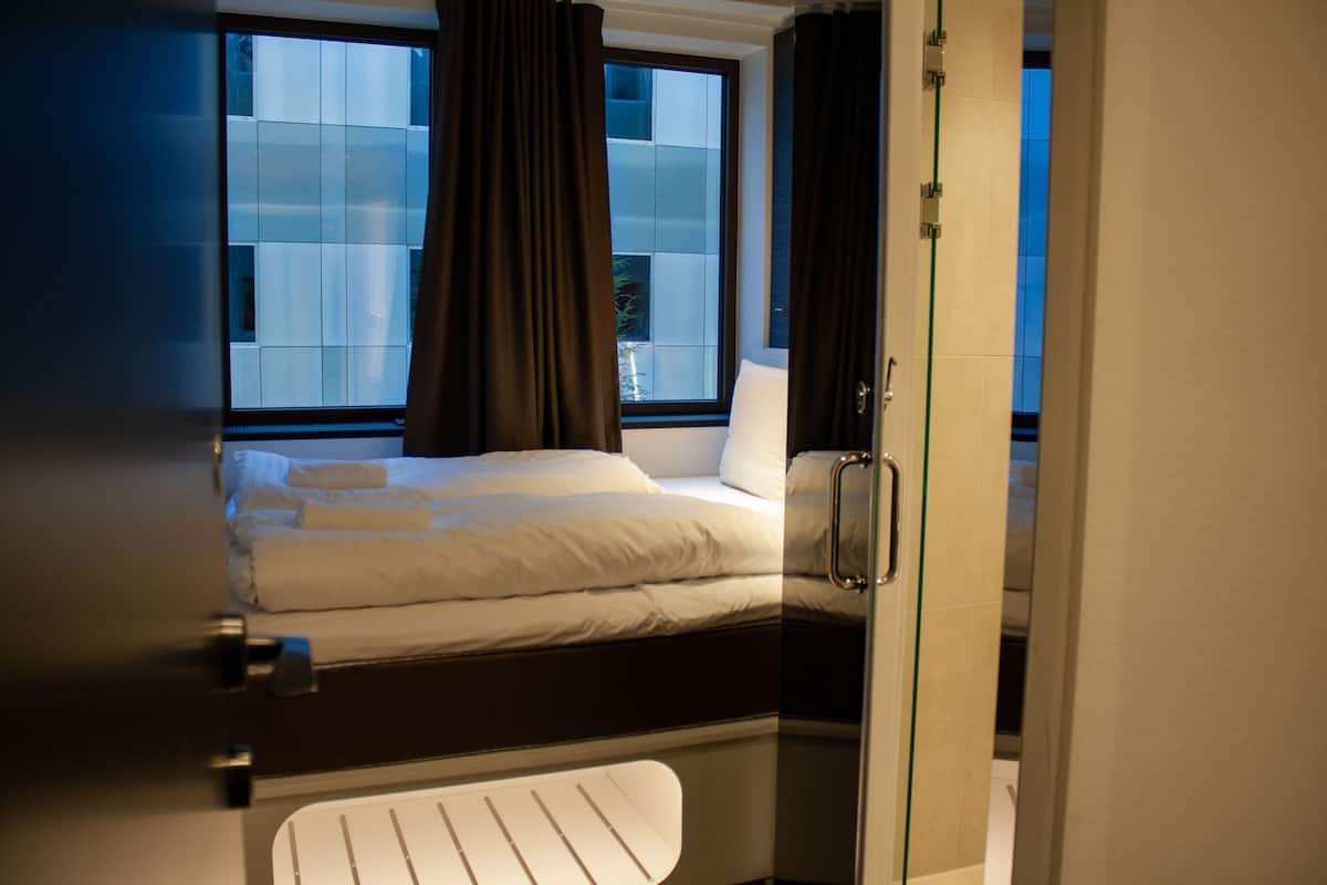 A compact bedroom with a bed, a window, and a door.