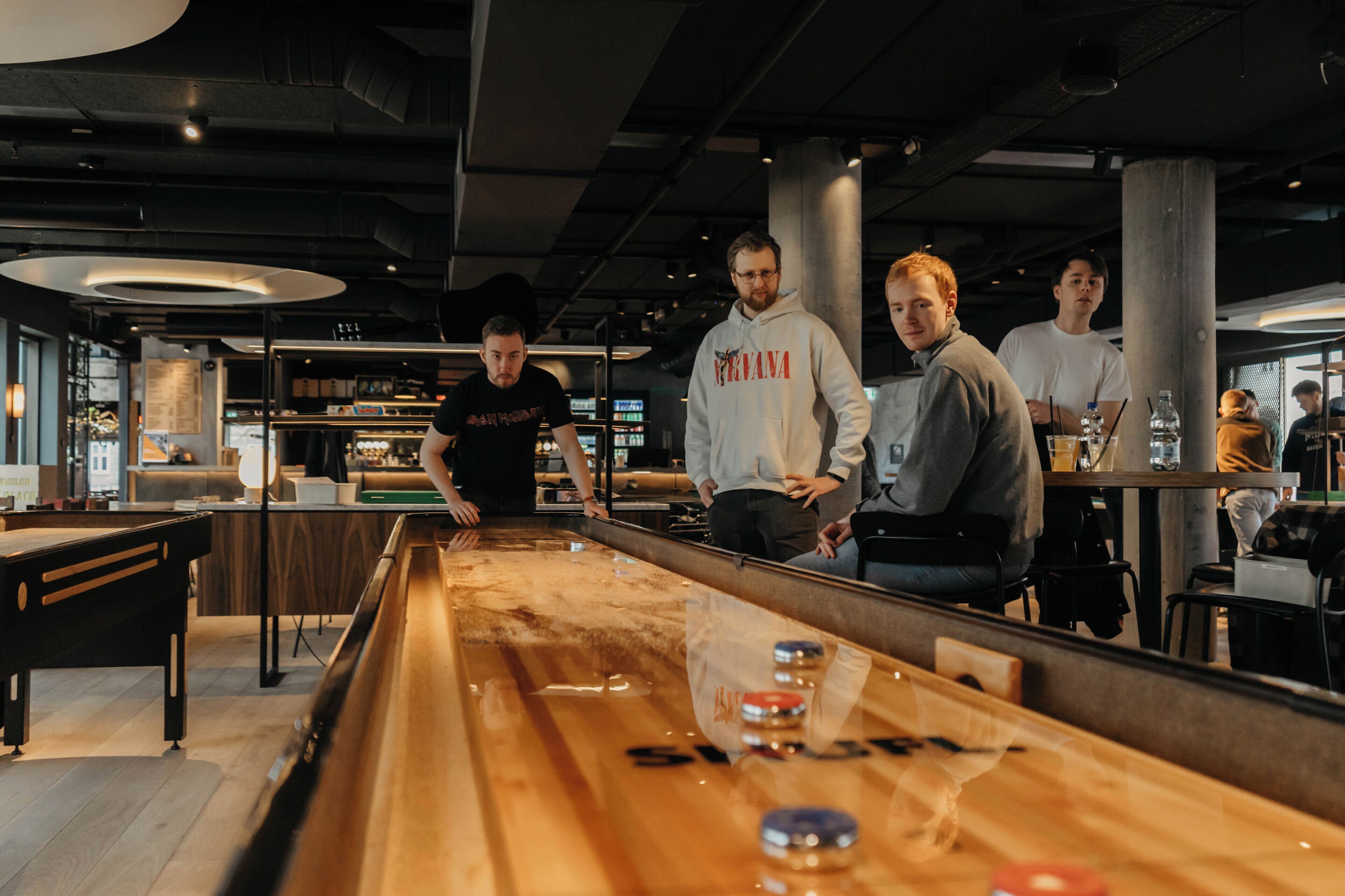 A billiards table in a modern indoor setting with a bar area in the background.
