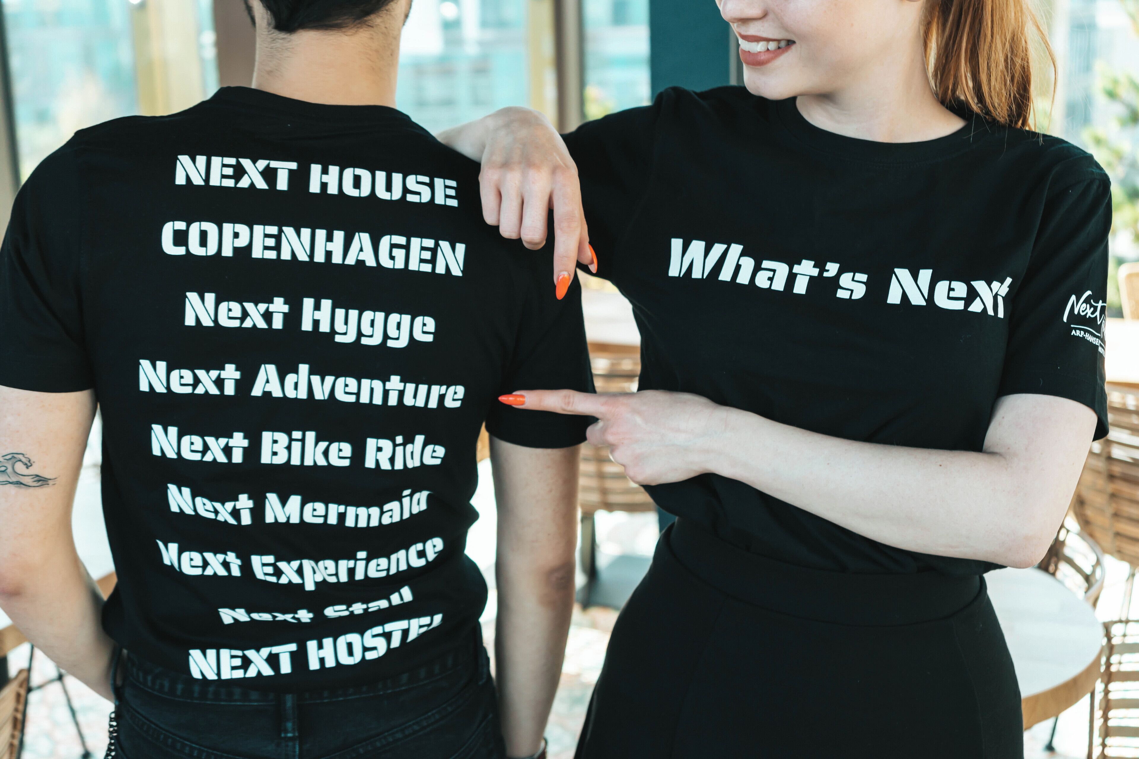 Two people wearing black t-shirts with text on the back.