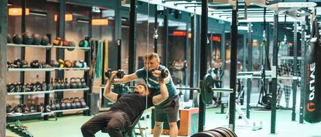 Un gimnasio con equipo de levantamiento de pesas y kettelbells.