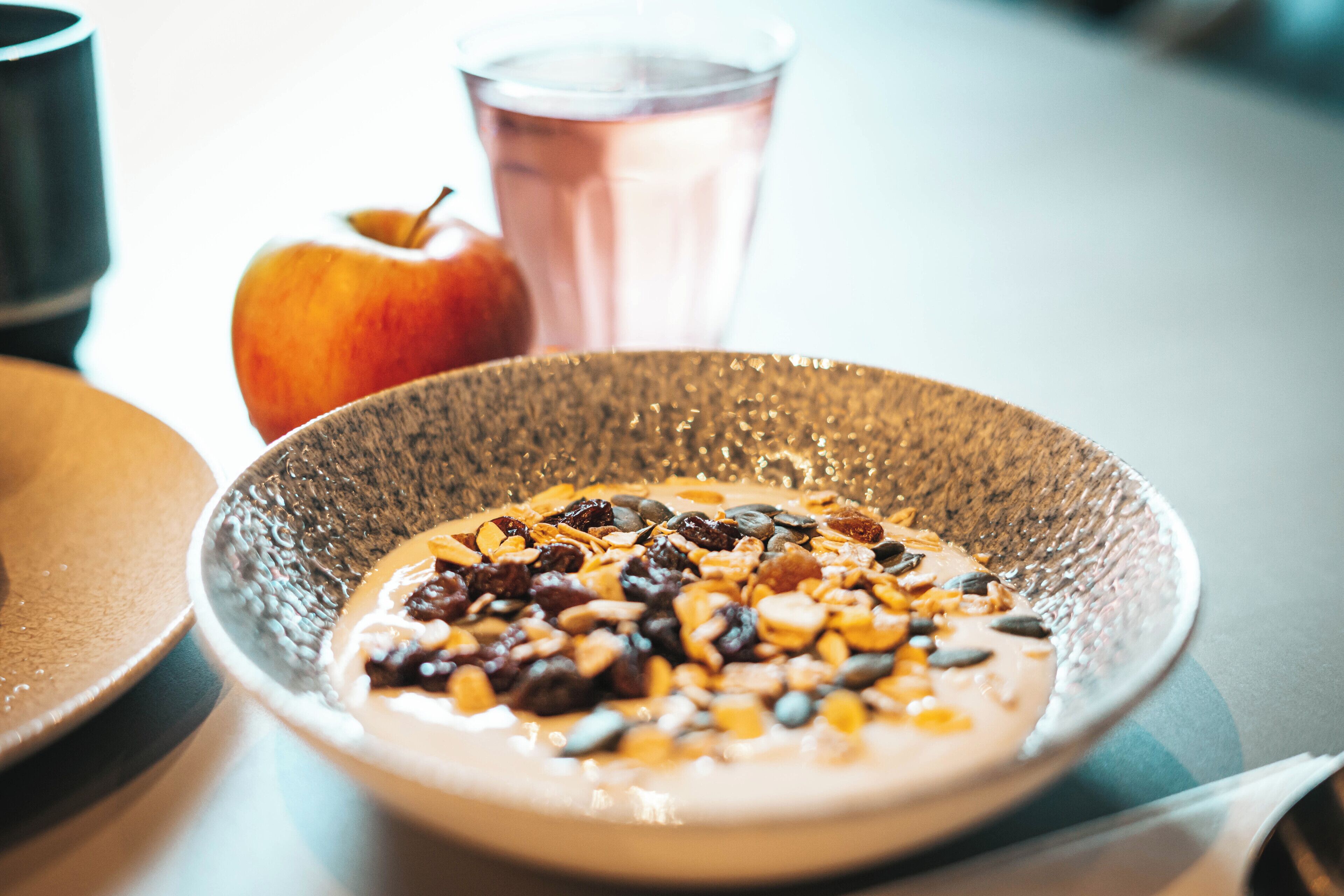 A bowl of cereal with fruits and nuts on a table.