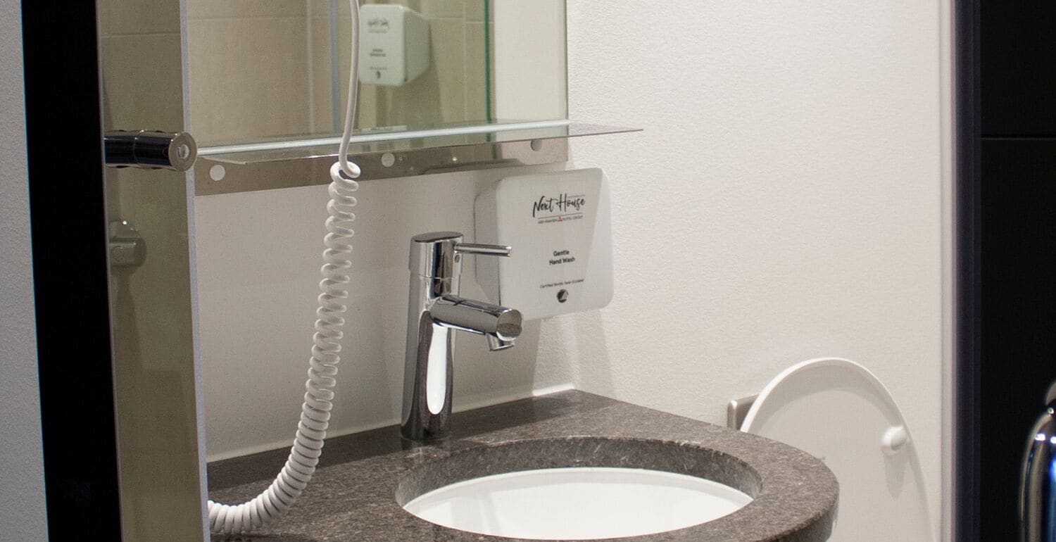 A modern bathroom with a granite sink, a chrome faucet, and a hand wash station.