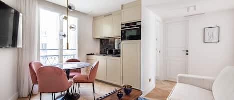 A modern apartment with a dining area, kitchenette, and living space.