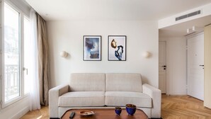 A modern living room with a sofa, a coffee table, and two framed artworks on the wall. - St Georges - Superb 3 Bedroom (Paris)
