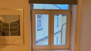 A room with a window overlooking a building, a radiator, and a chair. - Cosy Studio Apartment Near Florenc in Prague (Prague)