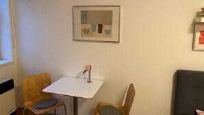 A small room with a white table, two chairs, a framed picture on the wall, and a grey sofa. - Cosy Studio Apartment Near Florenc in Prague (Prague)