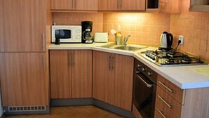 A kitchen with wooden cabinets, a microwave, a coffee maker, a toaster, and a stove. - Cosy Studio Apartment Near Florenc in Prague (Prague)